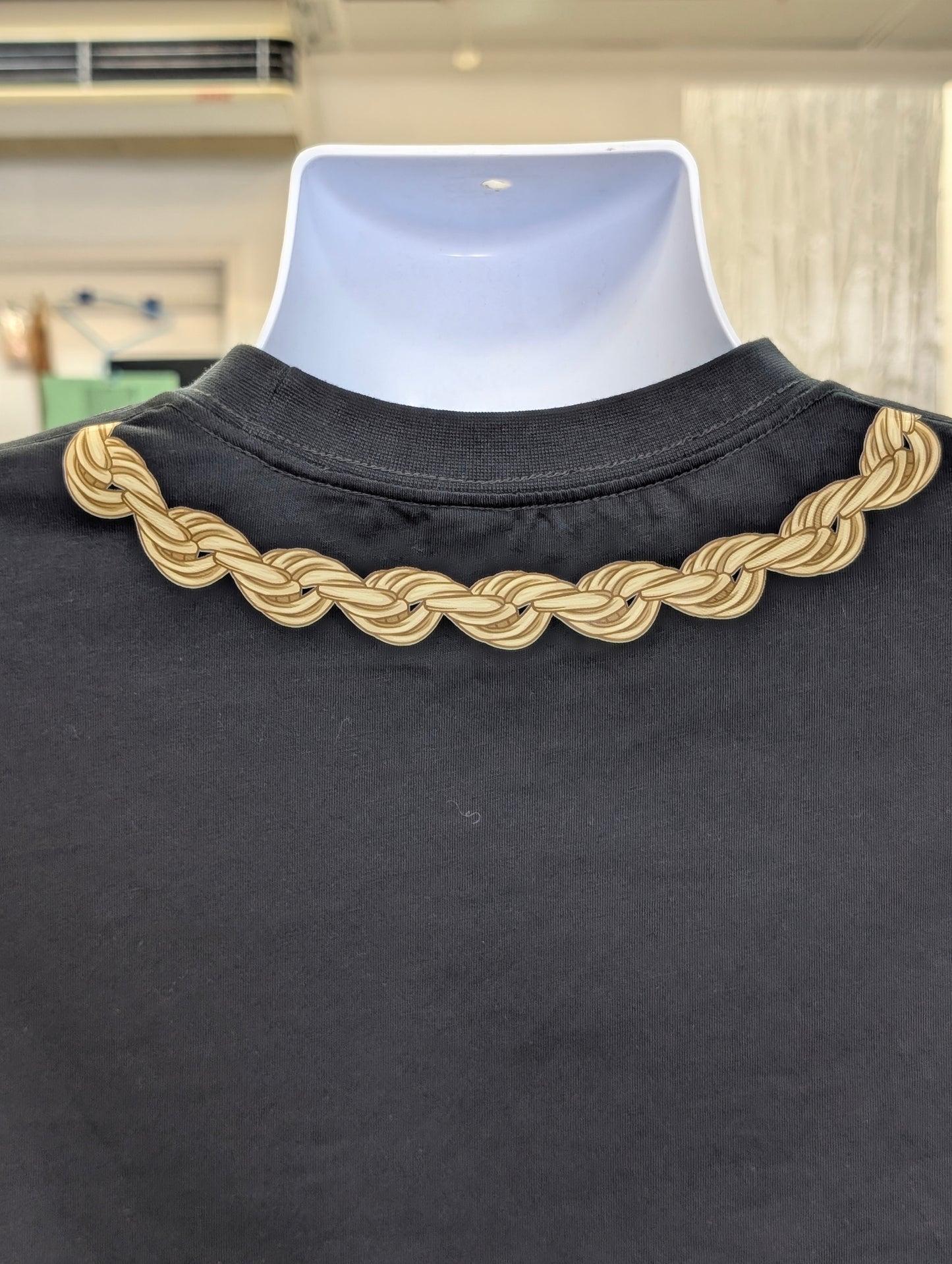 Black garment with a gold braided collar on a mannequin.