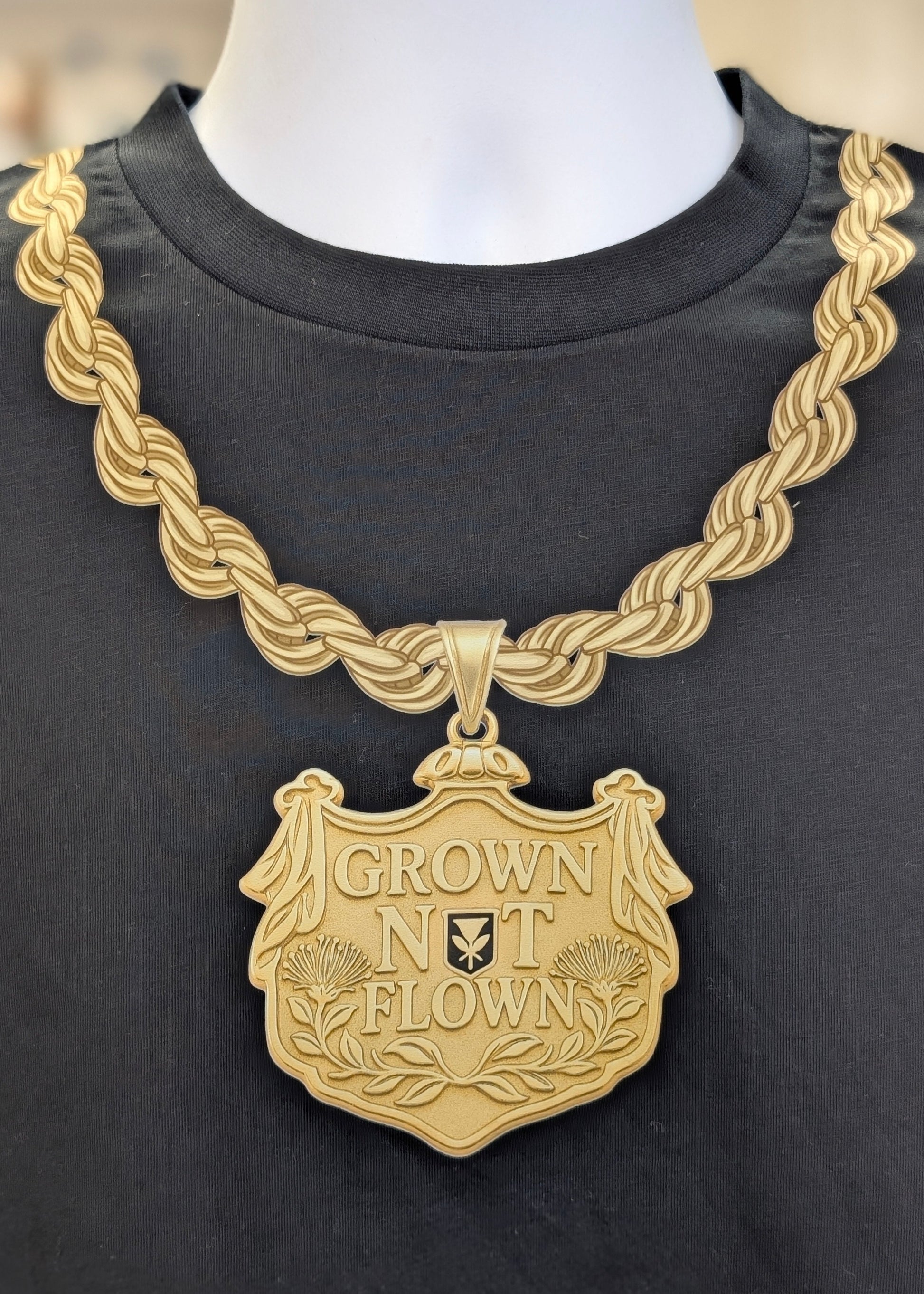 Gold necklace with 'Grown Not Flown' pendant on a black shirt