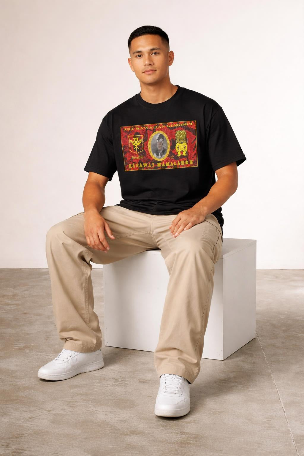 Model sitting while wearing King Kamehameha Kanaka Kala T-Shirt